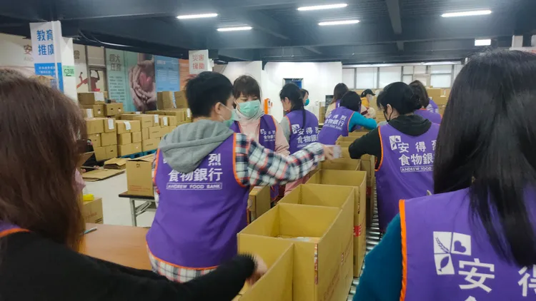 志工忙碌的包裝預備援助弱勢家庭的食物箱。黃子騰攝