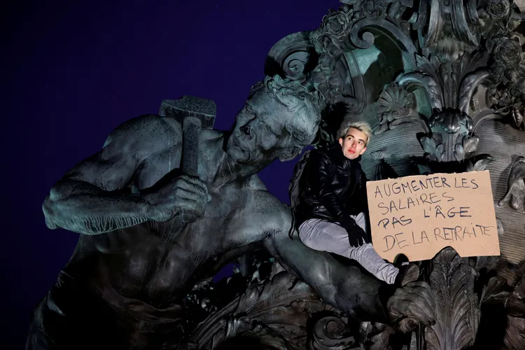 民眾手持「「提高工資，不是提高退休年齡」標語。路透