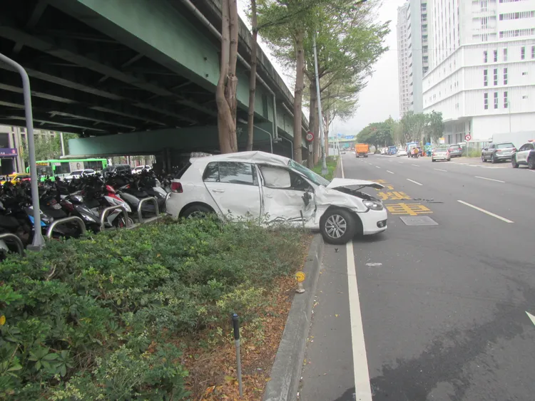 自小客慘遭撞及，整輛車被推擠到分隔島上。讀者提供