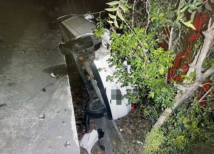 何男車輛停在路邊，無端被撞進溝內。讀者提供