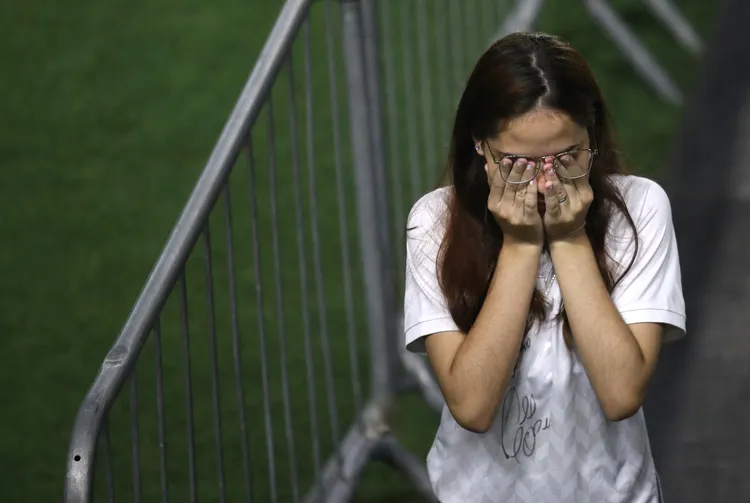 有球迷排隊過程掩面哭泣。路透社