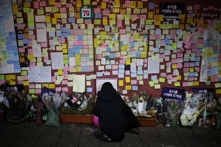一名女子2022年12月18日在梨泰院發生踩踏事故地的臨時留言追悼牆，哀悼罹難者。路透社