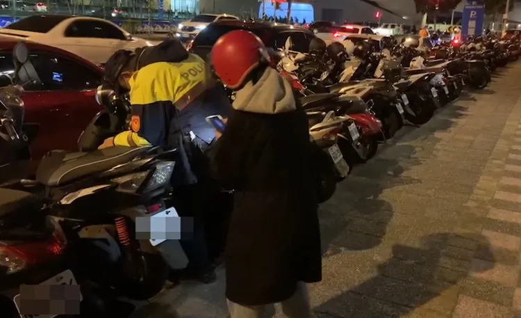 女子機車中柱卡在水溝蓋動彈不得，員警上前幫忙。警方提供