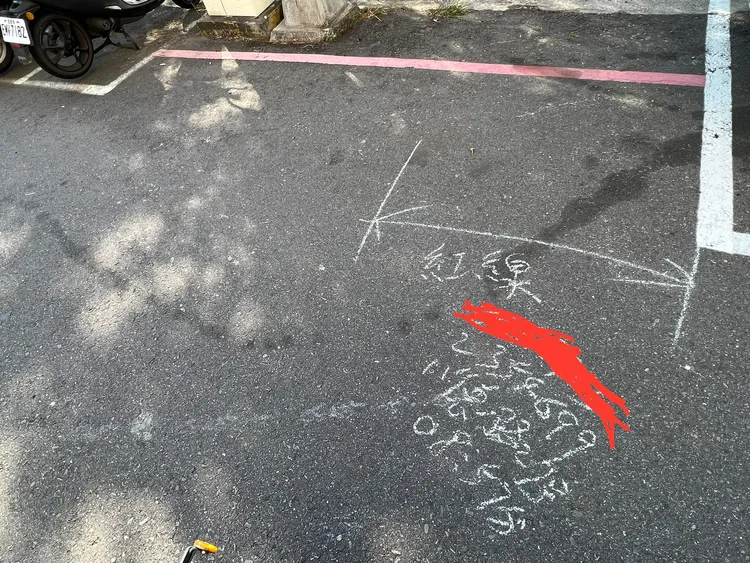 警方以粉筆在地面書寫，示意遭拖吊車主的車輛前輪超出停車格，停在紅線上。翻攝自臉書「爆廢公社二館」