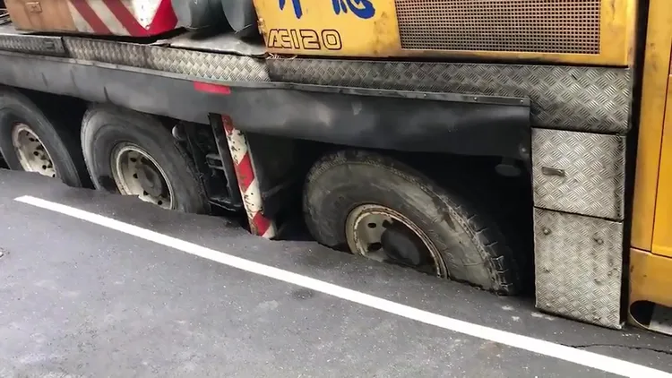 吊車輪胎有一半陷進柏油路面內。民眾提供