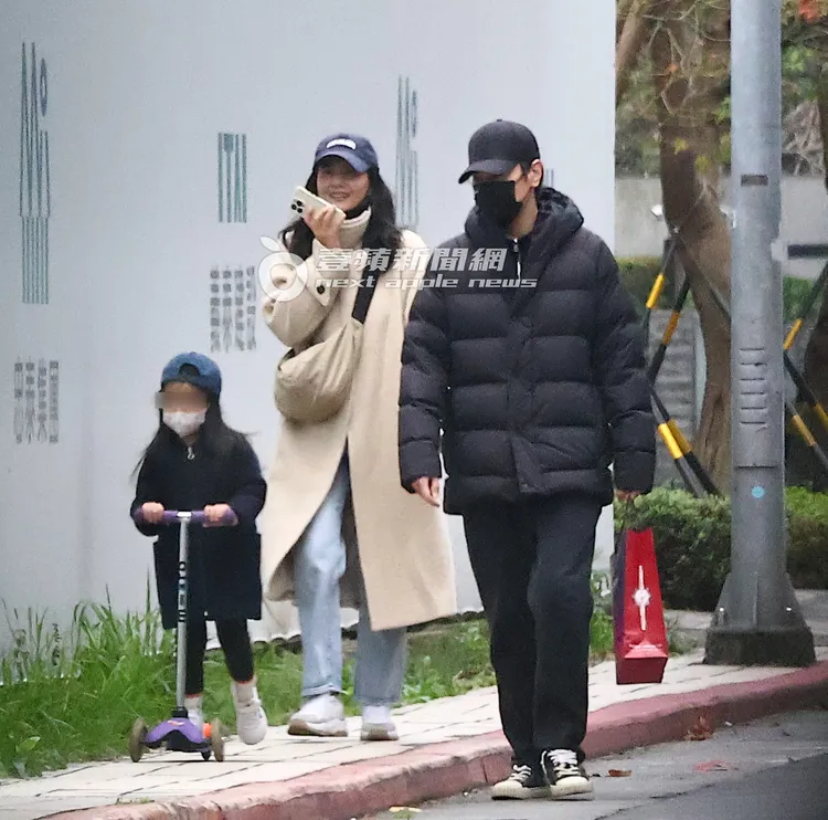 趙又廷（右）一身黑，拿著車輪牌鮑魚的紙袋看著女兒騎滑板車。特勤中心攝