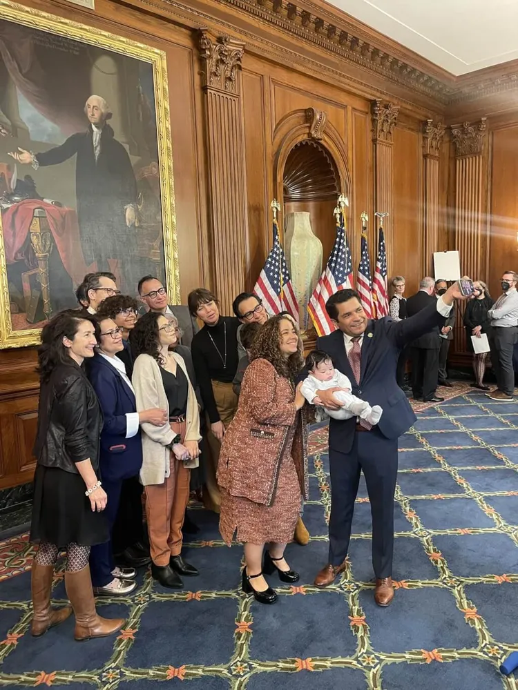 美國眾議員戈麥斯（右）月初抱著兒子穿梭在國會議場間，不少議員還趁著空檔時間，上前逗弄小孩。翻攝臉書/RepJimmyGomez
