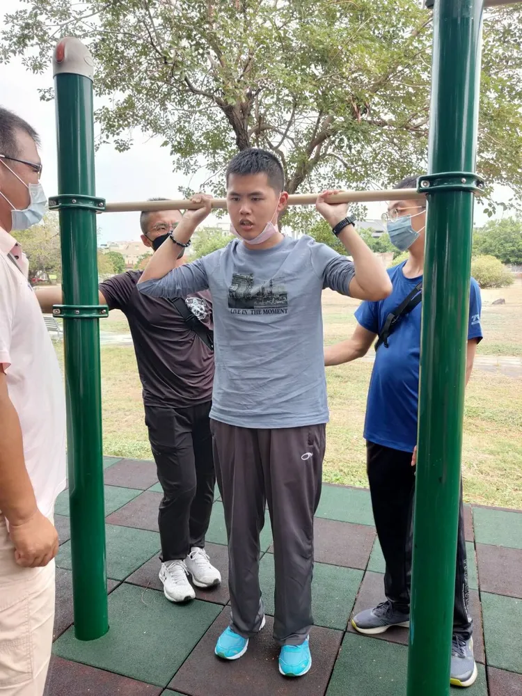 秦良丰在衛武營公園復健，試著舉手拉住單槓。秦爸爸提供