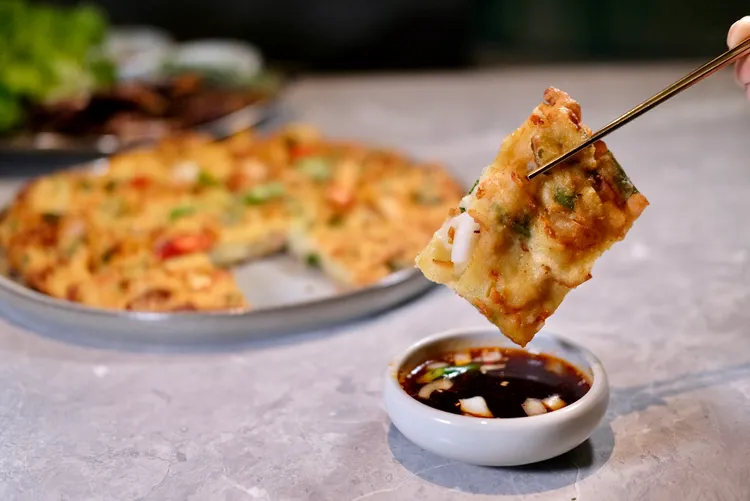 海鮮煎餅交到外皮酥脆，有著鮮蝦、花枝、蔥段、洋蔥等多種好料，可沾佐鹹甜「藥念醬」享用。葉盛耀攝