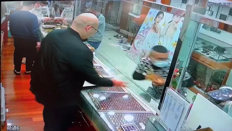 男子（右）趁隙拿走桌上金飾逃離。民眾提供