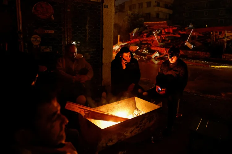 受災民眾靠著生火取暖。路透社