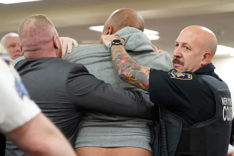 灰衣男子情緒激動，企圖衝向甘德倫，但遭攔下。美聯社