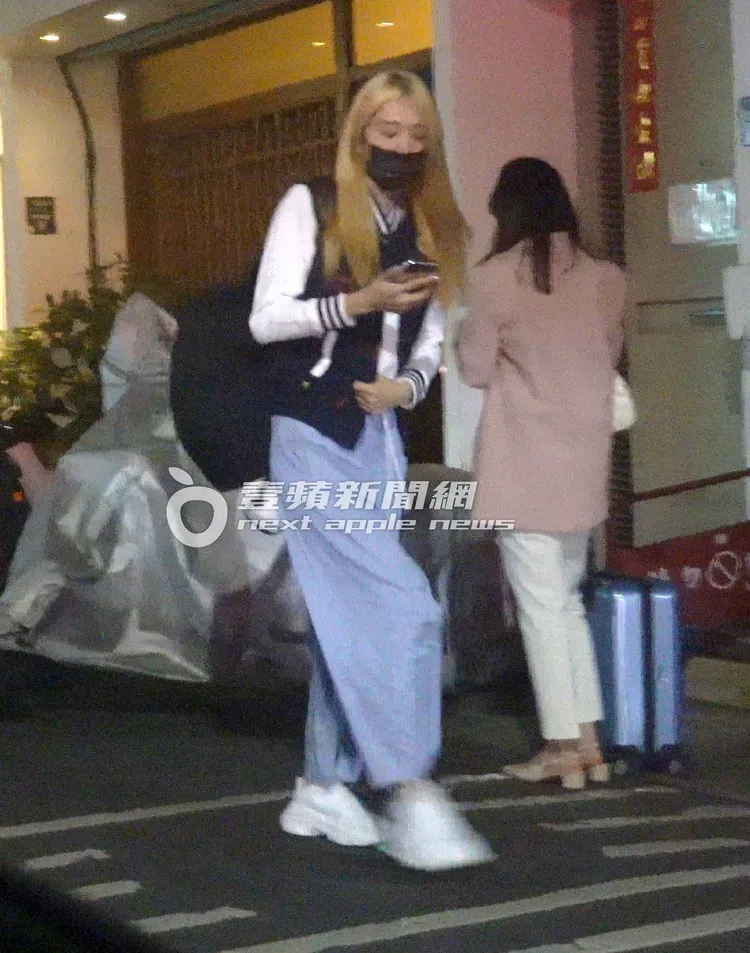 王心恬左手護肚，滑手機走在路上。特勤中心攝