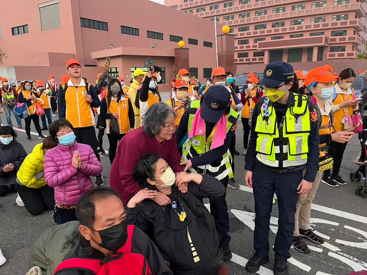 85歲婦人在女兒陪同下來鑽轎底，2名女警上前幫忙。民眾提供