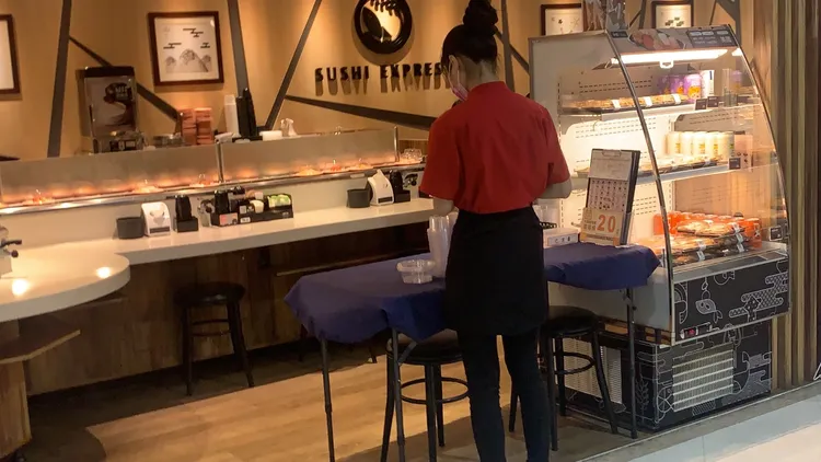 高雄一名婦人指她到爭鮮愛河店用餐，卻看到鄰座男子將摸過食物，再放回壽司軌道上。讀者提供