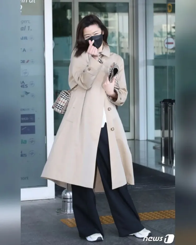 全智賢穿寬鬆的白T恤、寬黑褲和運動鞋，搭配BURNERRY米色Camden Heritage系列中長風衣，率性斜背BURBERRY經典格紋Lola包、手裡拿著格紋漁夫帽，風格輕鬆率性。翻攝giannajunfp IG