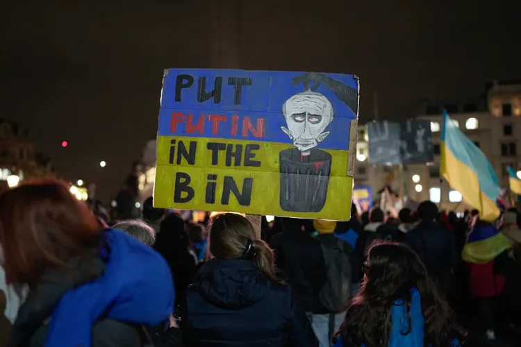 民眾持標語「把普丁丟垃圾桶」。美聯社