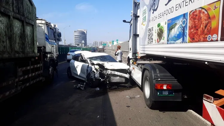 白色小客車遭兩輛聯絡車夾擊，180度大翻轉後、車頭嚴重毀損。讀者提供