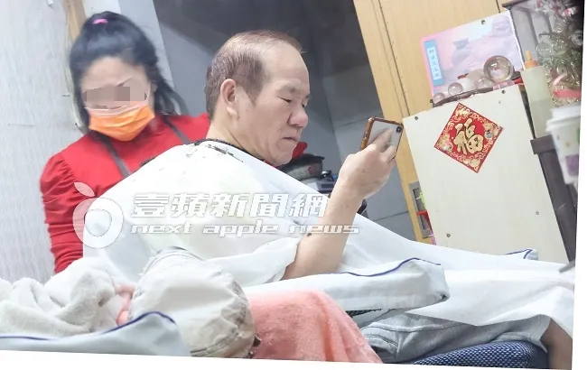 趙傳（右）在地方媽媽的服務下，邊看手機修剪頭髮，十分愜意。特勤中心攝