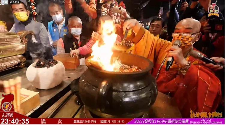 朝天宮住持法師以火勺掏引聖火到白沙屯的「火缸」中送入「香擔」。翻攝白沙屯拱天宮臉書