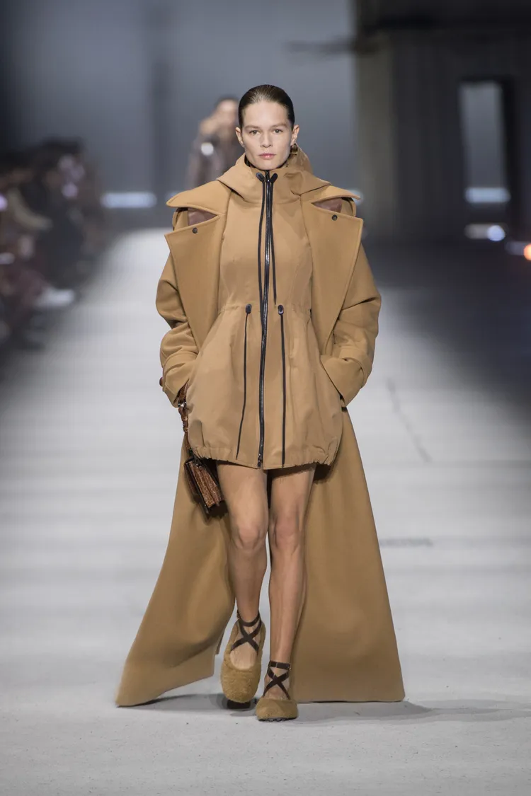俐落幹練的全長大衣，與內搭具有抽繩、連帽細節的洋裝，創造出極富趣味的視覺對比。品牌提供