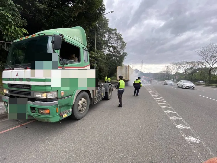 聯結車左後車輪冒煙起火，警員在現場管制交通。翻攝畫面