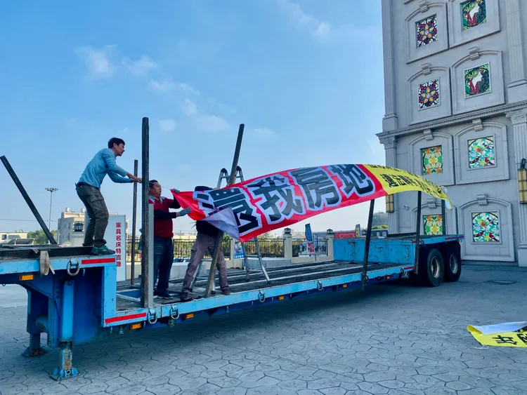 工人受雇卸下板車後掛布條。王志弘攝