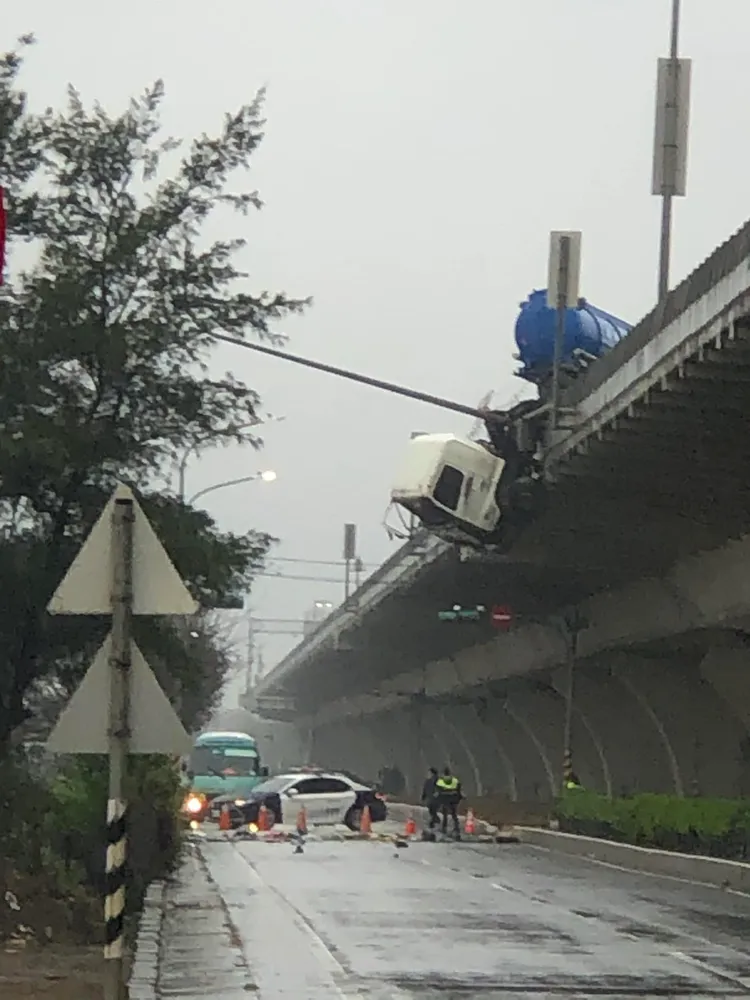 化學槽車車頭懸空在台61線與平面道路中間，而平面道路上多是護欄碎片，目前已封閉等待救援。翻攝《爆料公社／郭佑書》