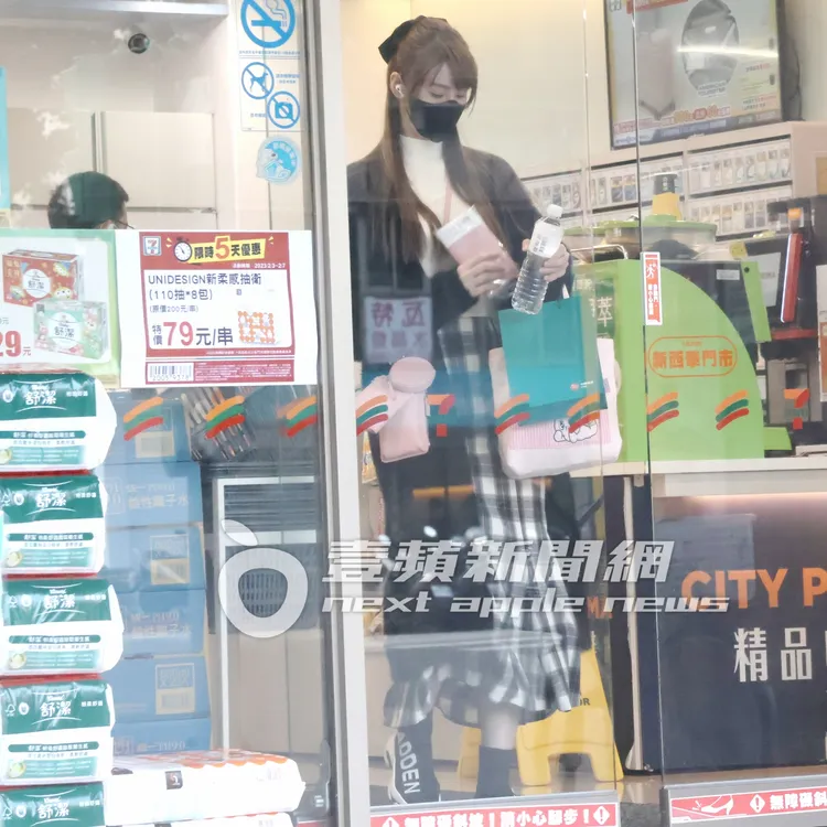 短今頭上綁蝴蝶結，身穿米白色高領毛衣，搭黑色外套，配上格子百褶裙。特勤中心攝