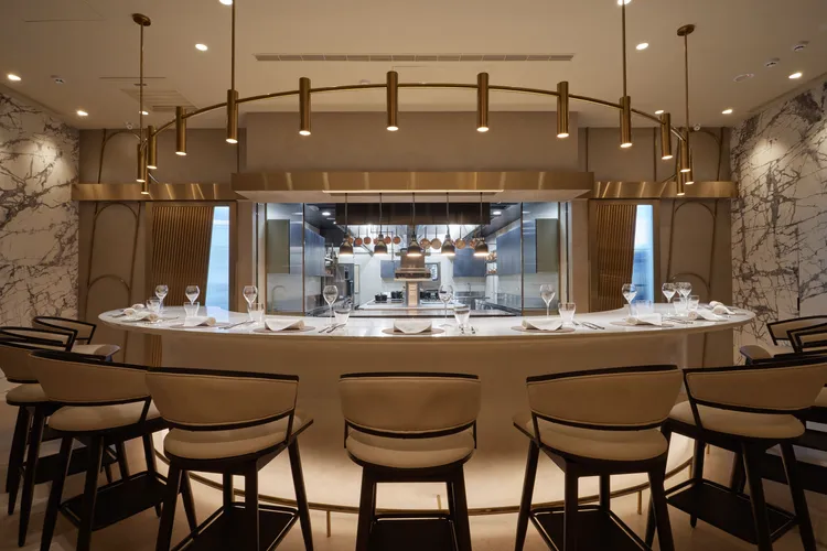 FRASSI客席以圓弧吧台環繞開放式廚房，讓賓客近身感受料理現場。業者提供