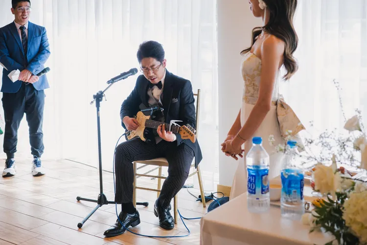 丁允恭在婚禮現場演奏吉他獻唱，新娘蔣婕妤在旁陶醉聆聽。翻攝蔣婕妤臉書