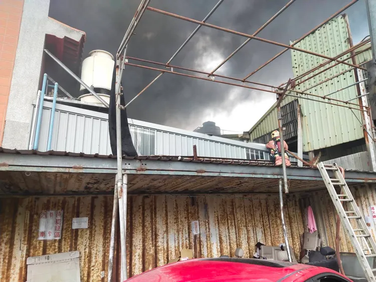 警消爬上工廠屋頂灌救。新北市消防局提供