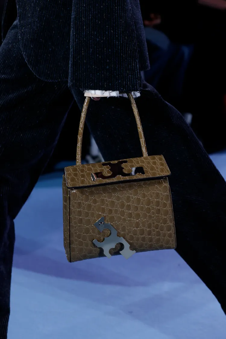 裝飾於手袋上搖搖欲墜的金屬T字logo，以及假損壞的鞋跟設計，皆呼應了「不完美之美」的核心精神。品牌提供