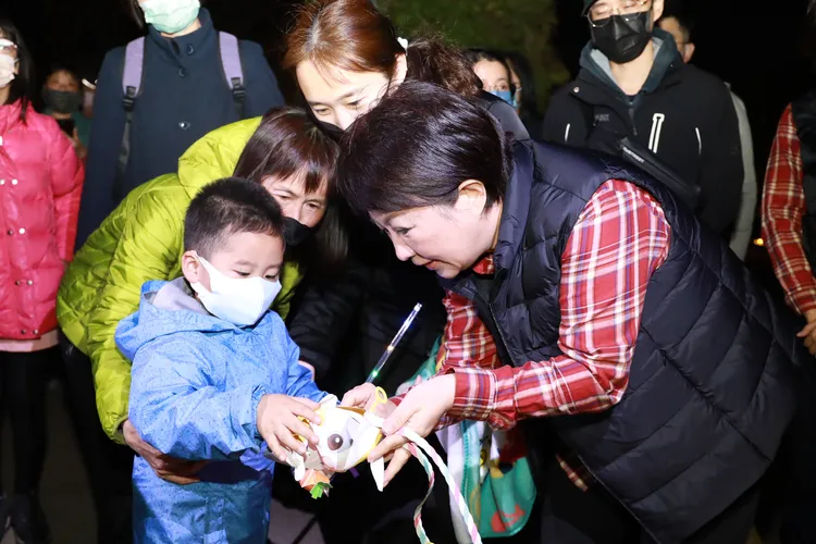 盧秀燕穿著最新潮流迷因「格紋襯衫配羽絨背心」，發放兔年小提燈給小朋友。市府提供