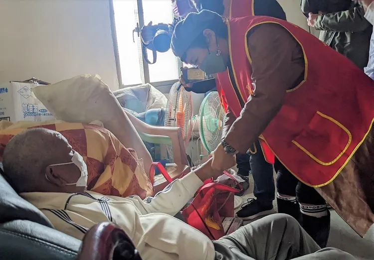 謝麗金(右)為獨居阿公塗抹護手霜。艾迪昇傳播提供