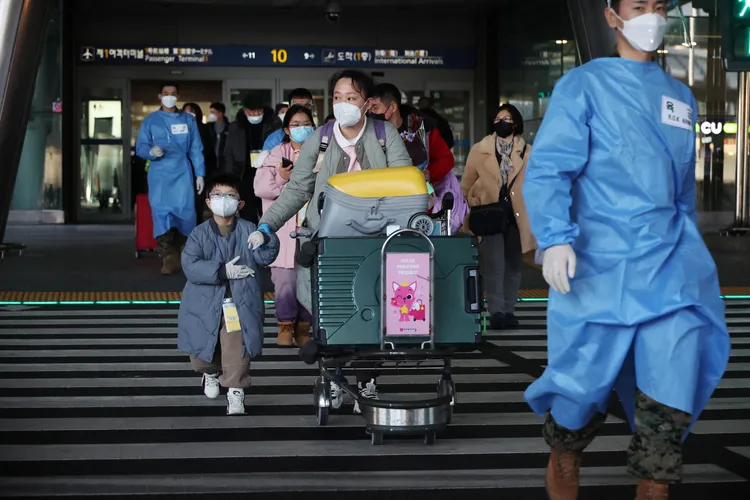 南韓仁川機場的軍警穿著隔離衣，領著來自中國的旅客接受新冠檢測。路透