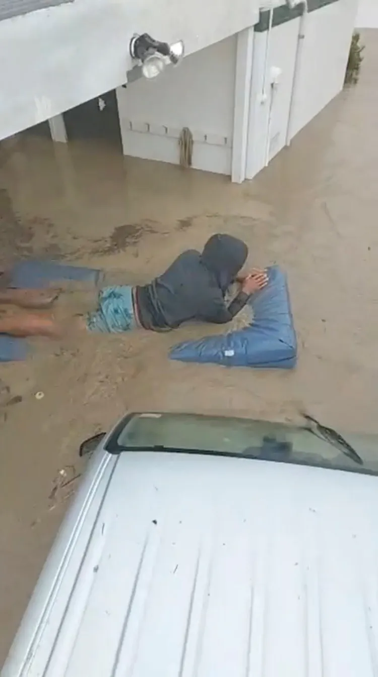 紐西蘭民眾在泥水中，乘著充氣漂浮物。美聯社