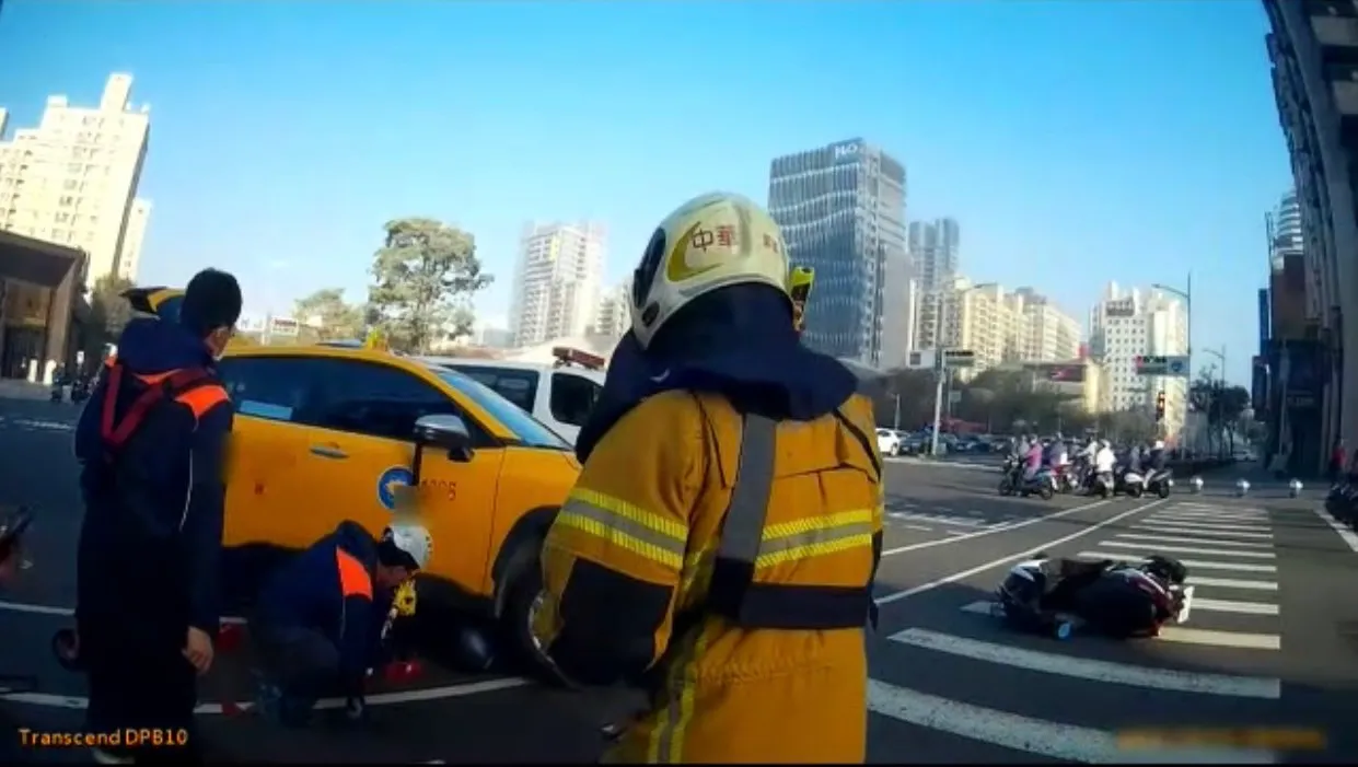 警消蹲下查看困在計程車黃男的情況。讀者提供