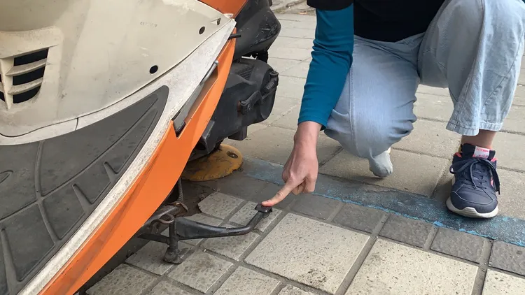 李小姐以其他摩托車示意說明，指她停車立中柱時，中柱彈起插入她的左腿裡。吳慧芬攝