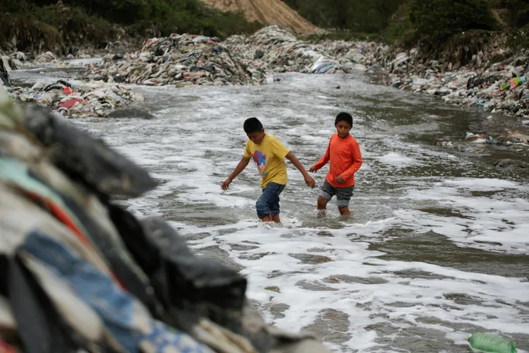 小朋友在汙染的河中涉水而過。路透社