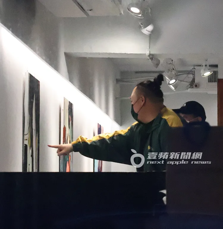 大淵（左）指著畫作與藝廊人員討論。特勤中心攝