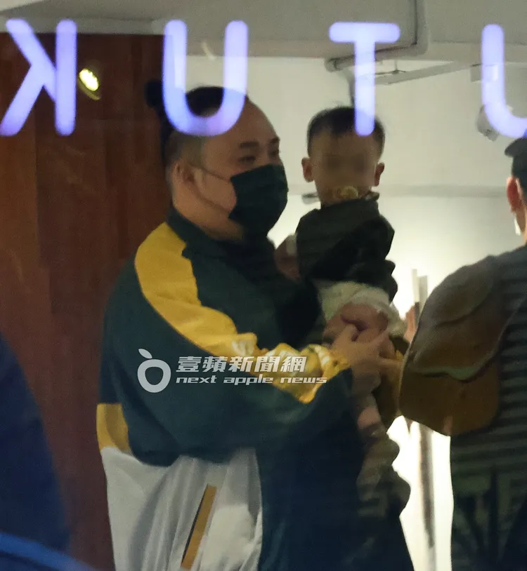 大淵（左）熟練的抱著兒子與友人聊天。特勤中心攝