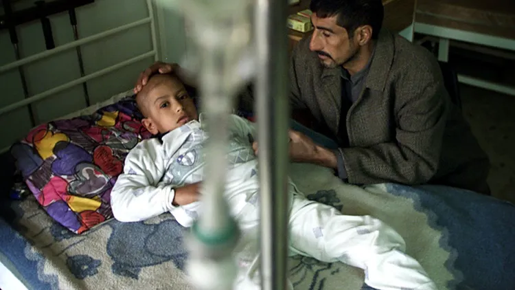 伊拉克戰爭後，戰區附近的居民罹患癌症的病例變多。圖為當地伊拉克父親照顧罹患血癌的小孩。路透社資料照片