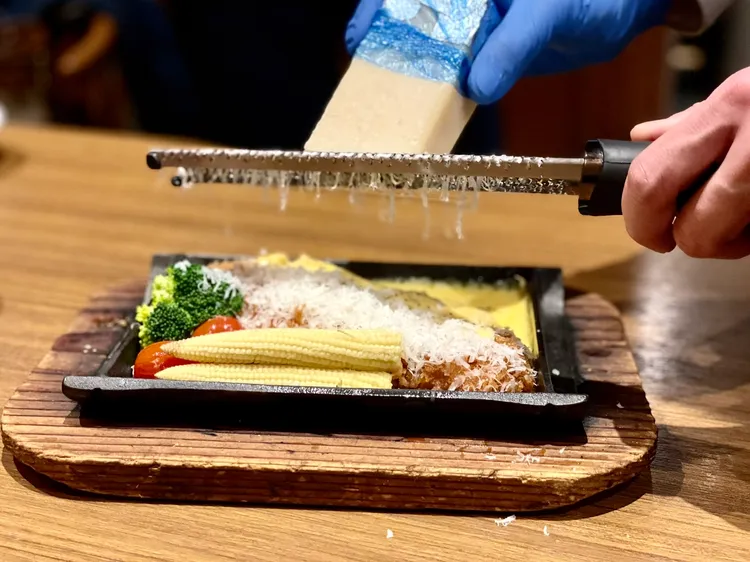 「熔岩起士里肌豬排套餐」淋上切達起士與莫札瑞拉起士混合成的濃稠醬汁後，還會桌邊現刨滿滿的帕達諾起士絲。曾仲葳攝