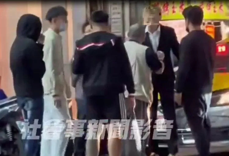 西裝騎士與運將站在路旁大聲爭執，引起路人圍觀。翻攝社會事新聞影音
