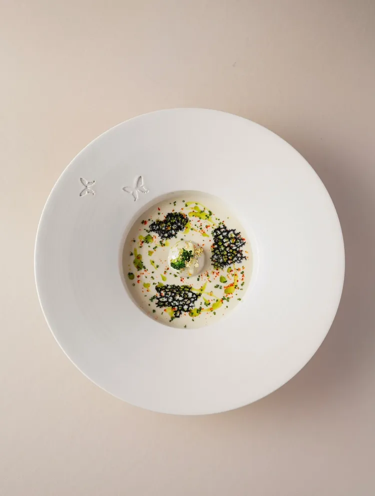 「Papillon」的湯品以白花椰菜做湯底，中間佐以帕瑪森起司包裹的豬肉凍，搭配上些許的阿根廷青醬及香草增添清爽的氣息。讀者提供