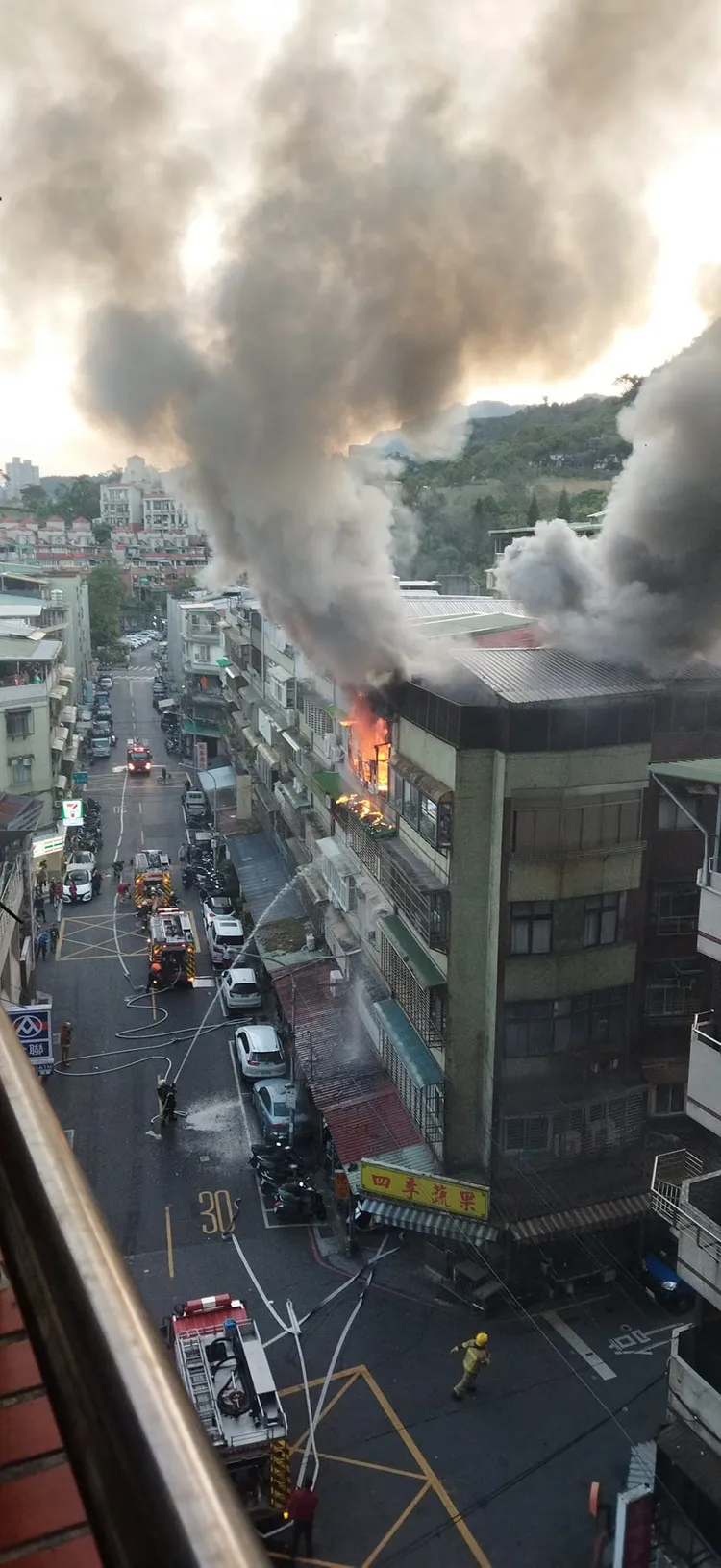 公寓頂樓竄出大量濃煙，警消拉設水線搶救。翻攝臉書《信義區三兩事》