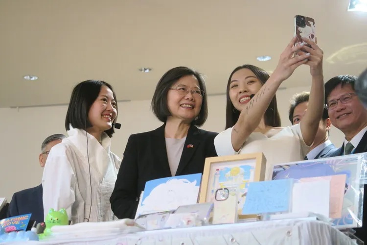 總統蔡英文（中）出訪友邦過境紐約，30日在駐紐約辦事處與近期赴當地參展的插畫家張雅晴（左）、鍾逸婷（右）玩自拍。中央社