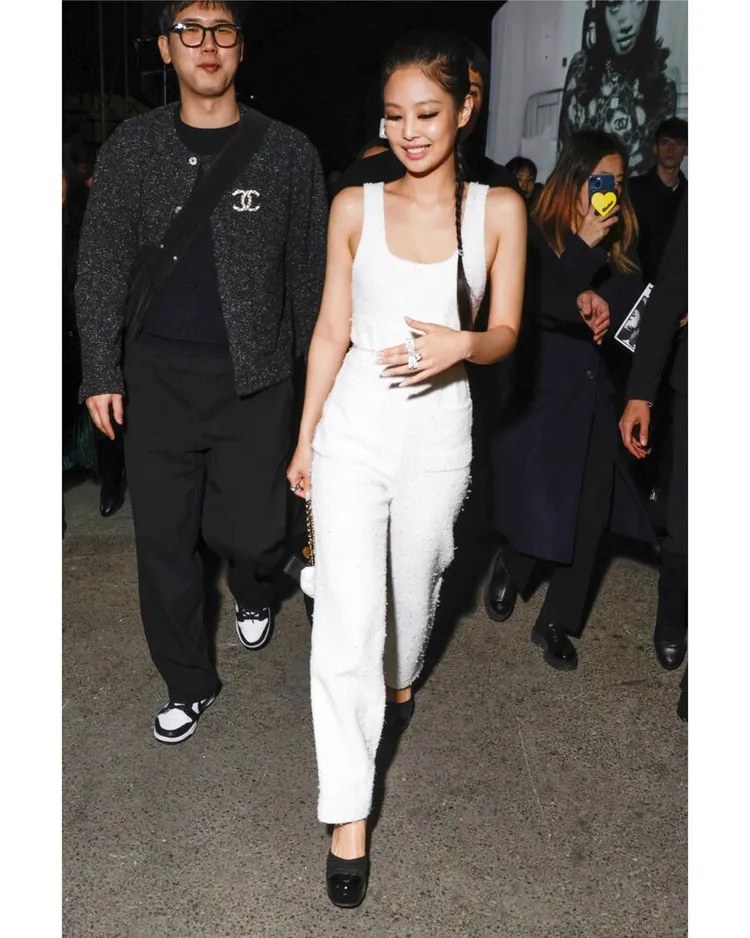 Jennie畫上貓眼妝與髮辮造型，穿著白色斜紋軟呢連身褲裝、黑色高鞋，展現了酷帥又甜辣的時髦風格。翻攝blackpinkoutfit__ IG