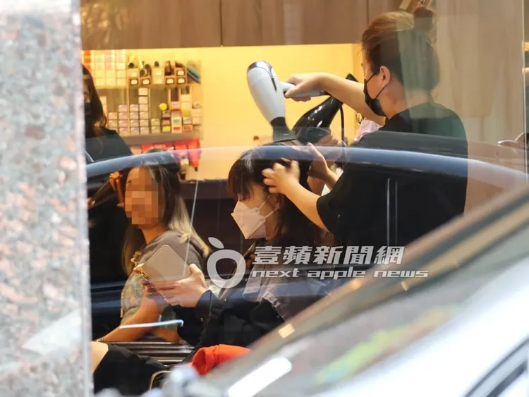 楊智惠在髮廊邊滑手機，一邊交給兩位設計師助理幫忙吹頭髮。特勤中心攝